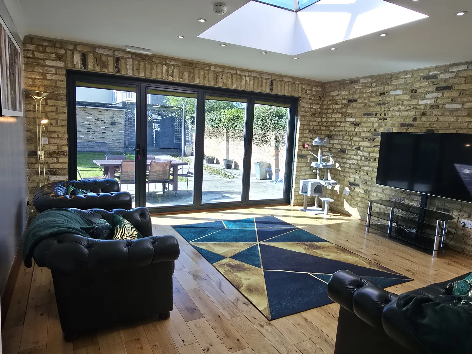 The lounge at Sawadi House with exposed brick, a skylight and doors onto the garden